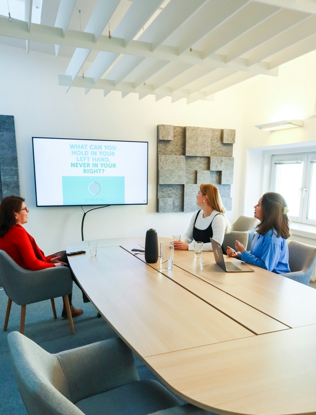 Tre donne collaborano attorno a un tavolo da conferenza durante una sessione di formazione.