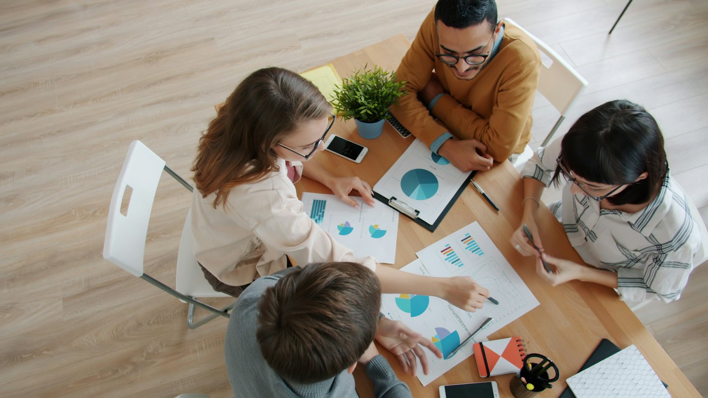 Professionisti aziendali che collaborano attorno a un tavolo con documenti.